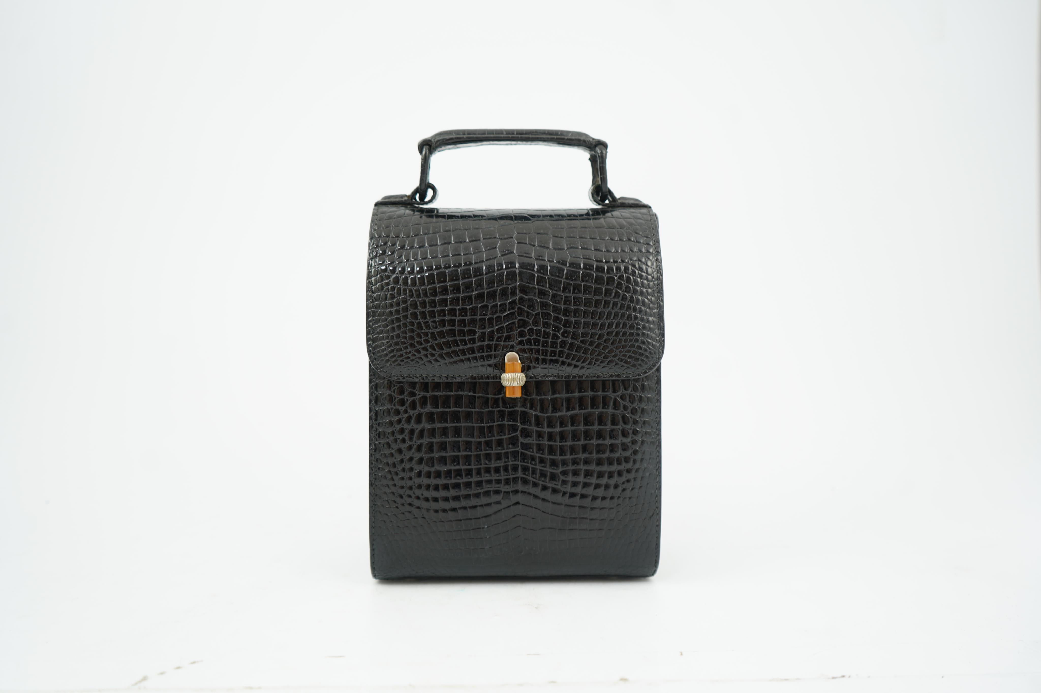 A stylish 1930’s lady’s Asprey of London, black lizard skin evening bag with ornamental amber coloured Bakelite clasp. 23cm high from handle to base. Condition- some internal scratches to lining as expected for age and u